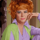 Not everyone can pull off a purple and lime green pantsuit with turquoise eyeshadow, but by God she does it.